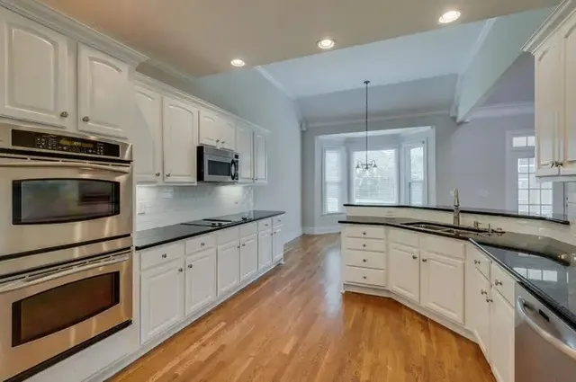 a kitchen with granite countertop white cabinets white stainless steel appliances and a sink