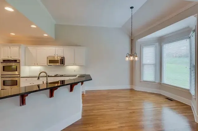 a kitchen with stainless steel appliances granite countertop a sink a stove and a wooden floors