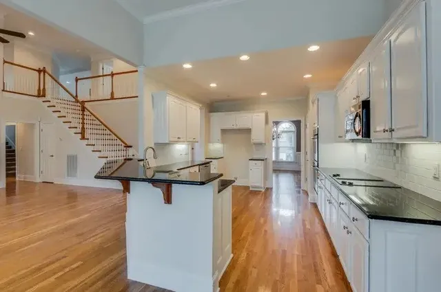 a kitchen with stainless steel appliances granite countertop a refrigerator a stove and a wooden floors