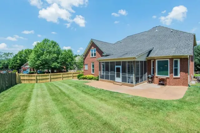 a view of a house next to a big yard and potted plants