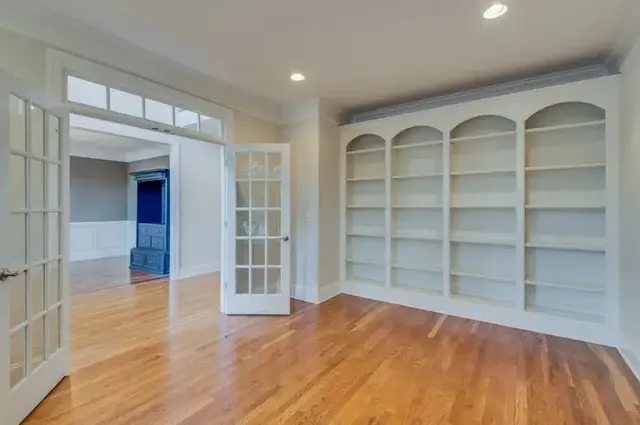 a view of an empty room with wooden floor and a window