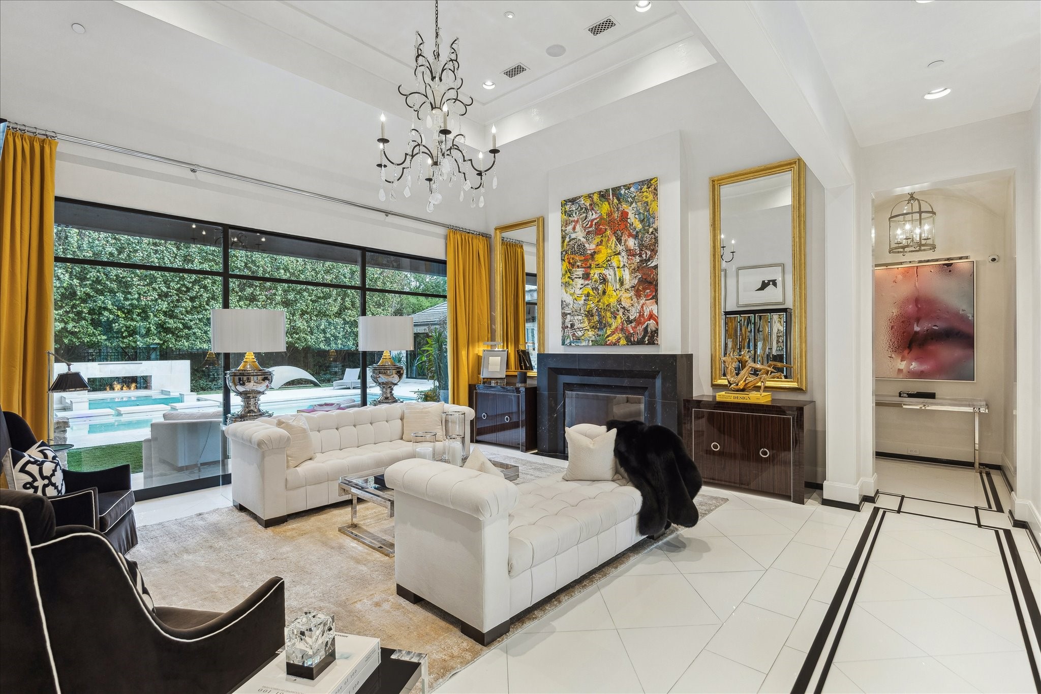 220 Merrie Way Lane Houston, TX 77024 - Photo 6 of 50 The formal living room rises to 17-foot vaulted ceilings, crowned by a striking iron-and-crystal chandelier. Fleetwood doors open completely to the terrace and pool, while a marble-framed fireplace adds classic sophistication.