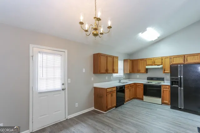 a kitchen with stainless steel appliances granite countertop a refrigerator a sink dishwasher a stove and white countertops with wooden floor