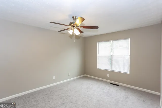 an empty room with a window and a fan