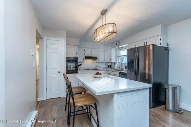 a kitchen with stainless steel appliances a dining table chairs refrigerator and microwave