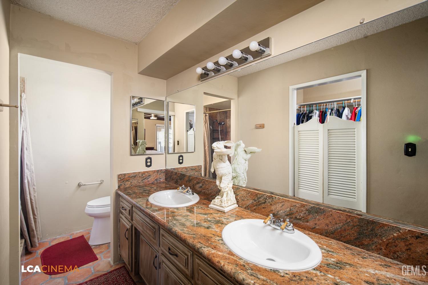 Undisclosed Address Bakersfield, CA 93309 - Photo 18 of 30 a bathroom with a granite countertop sink a mirror and a toilet