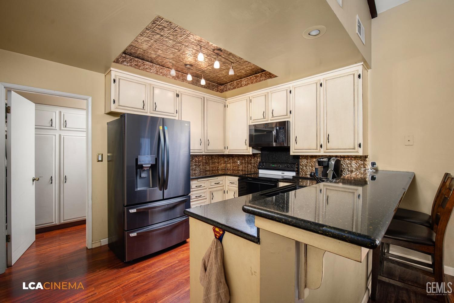 Undisclosed Address Bakersfield, CA 93309 - Photo 9 of 30 a kitchen with a refrigerator a microwave a sink and wooden floor