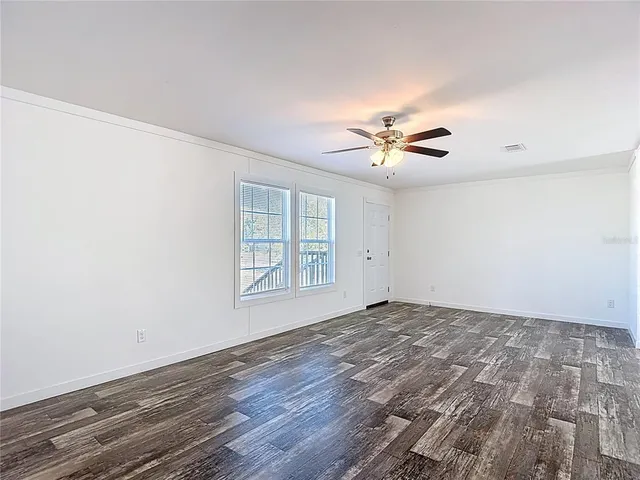an empty room with windows and ceiling fan