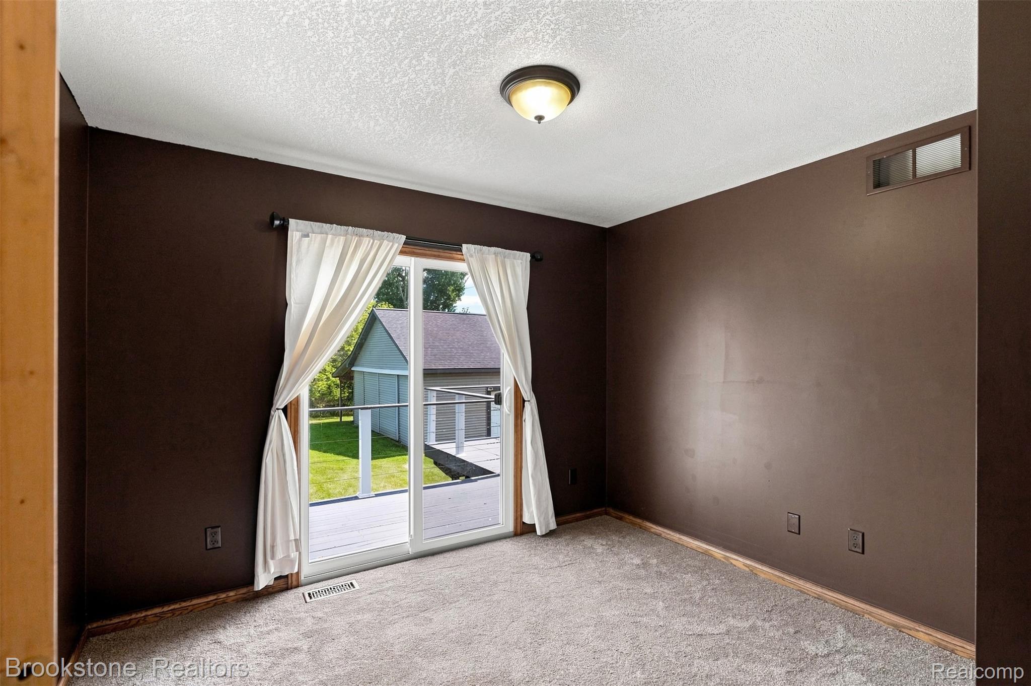 1775 Dutcher Road Howell, MI 48843 - Photo 12 of 41 Expansive sliding glass door, neutral-toned carpeting, flush-mount ceiling light, and direct access to an outdoor deck