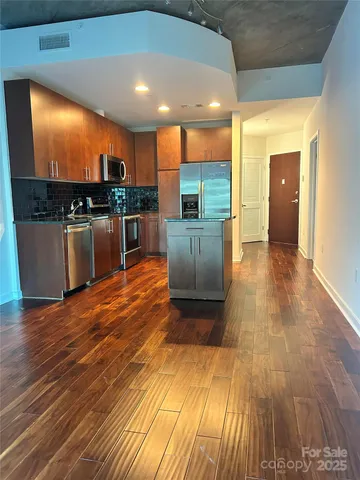 a view of kitchen with kitchen island a sink wooden floor and a counter top space