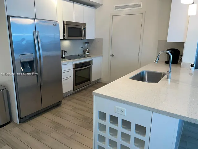 a kitchen with granite countertop a refrigerator and a sink