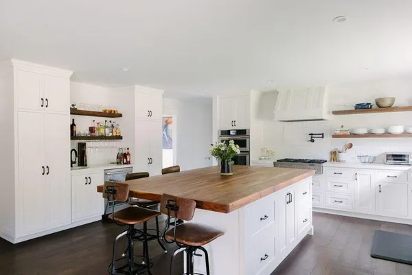 a kitchen with stainless steel appliances a stove a table chairs and a refrigerator