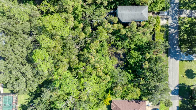 an aerial view of residential house with outdoor space and trees all around