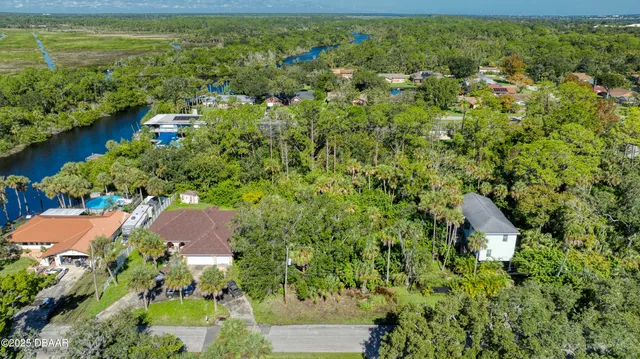an aerial view of residential houses with outdoor space and trees