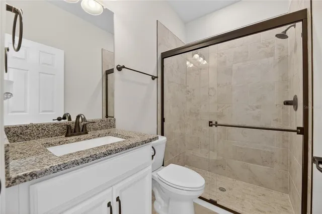 a bathroom with a granite countertop sink mirror vanity and toilet