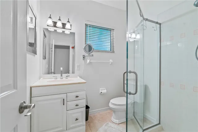 a bathroom with a toilet a sink a mirror a vanity and shower