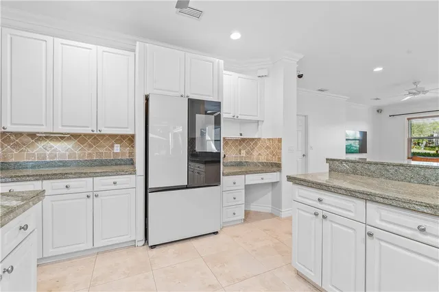a kitchen with granite countertop white cabinets and refrigerator