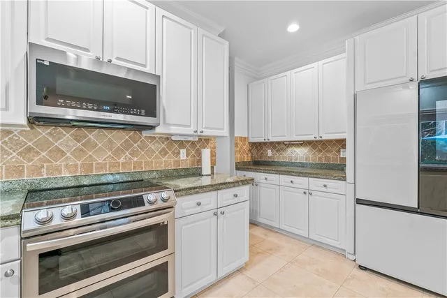 a kitchen with granite countertop white cabinets stainless steel appliances and a counter space