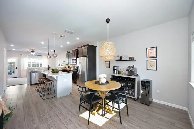 a kitchen with a dining table chairs wooden floor and appliances