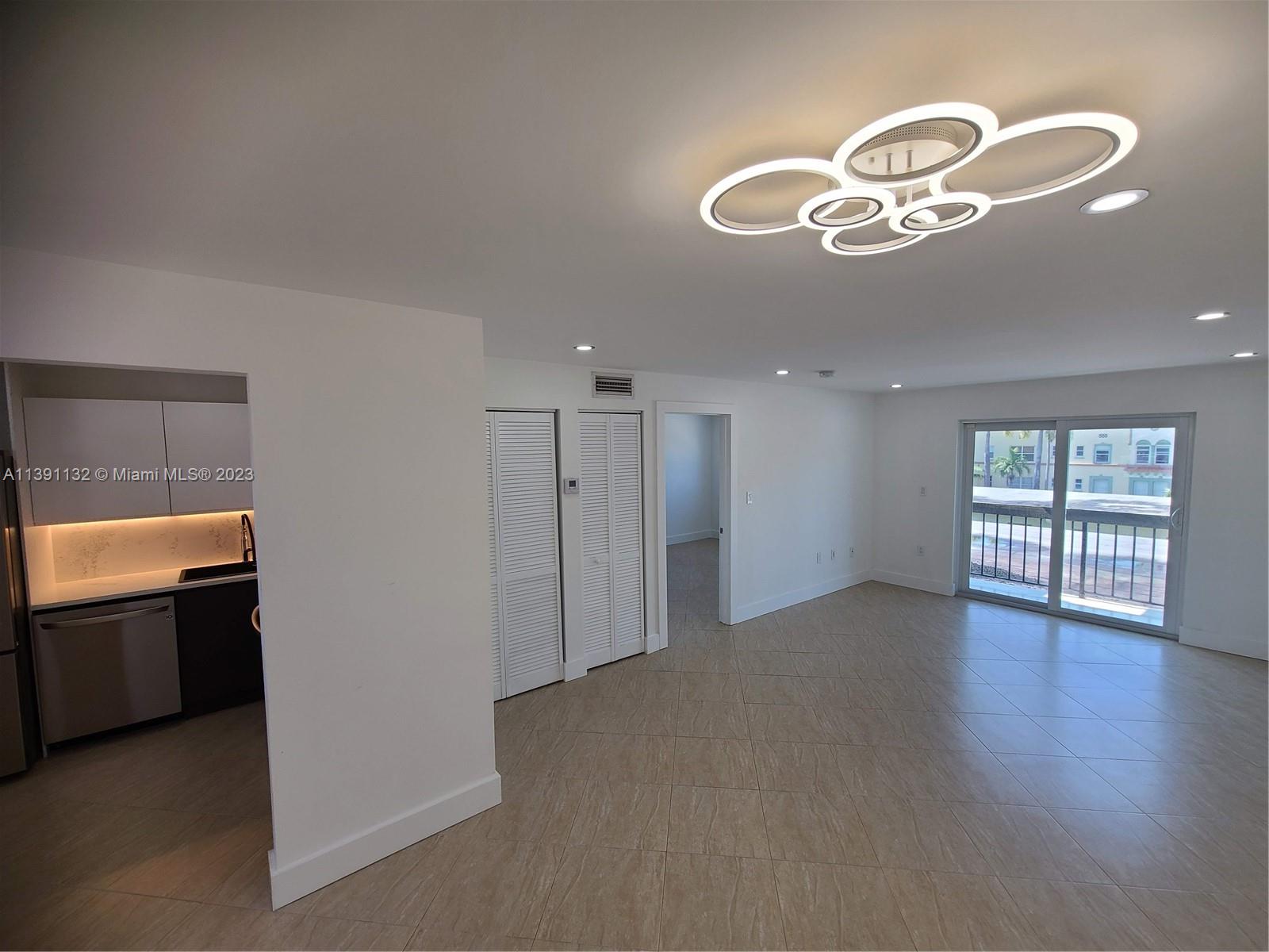 an empty room with wooden floor cabinet and windows