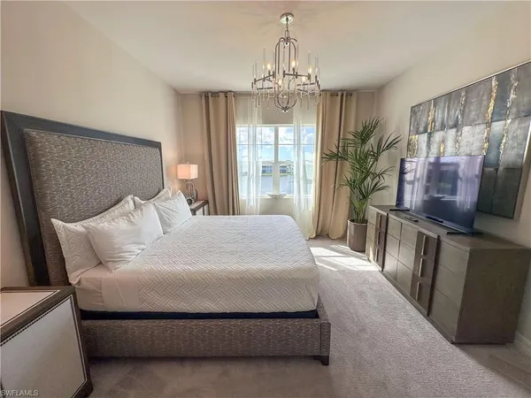 a bedroom with a bed and a flat tv screen on dresser
