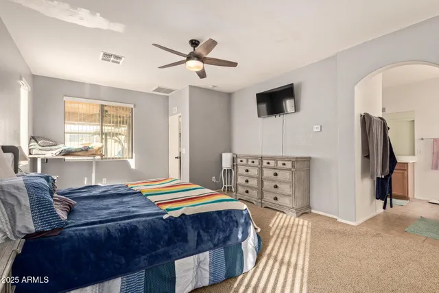 a bedroom with a bed and a flat tv screen on dresser