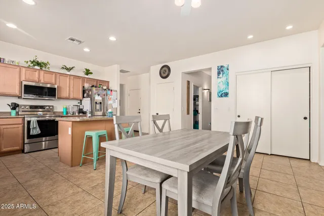 a kitchen with stainless steel appliances granite countertop a kitchen island a stove a table and a refrigerator