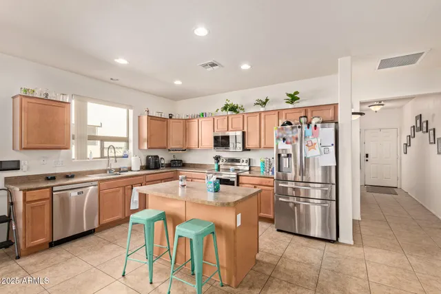 a kitchen with stainless steel appliances a refrigerator a sink a stove a dining table and chairs