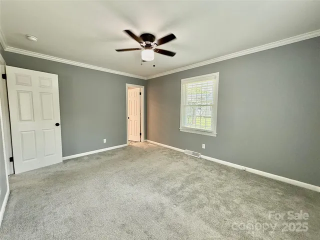 an empty room with windows and fan