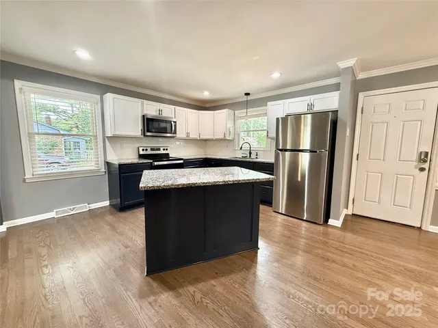 a kitchen with stainless steel appliances granite countertop a refrigerator a sink dishwasher a stove with wooden floor and cabinets