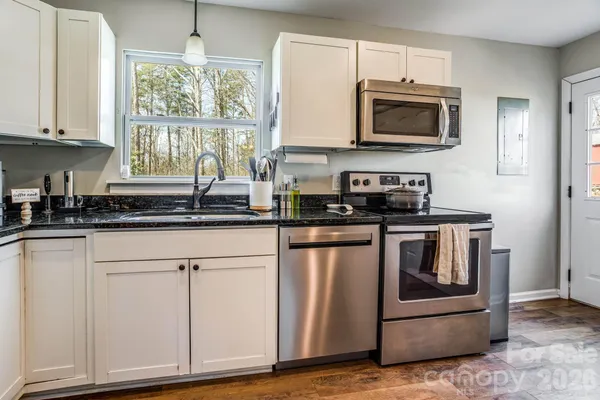 a kitchen with stainless steel appliances granite countertop a stove a microwave and a white cabinets
