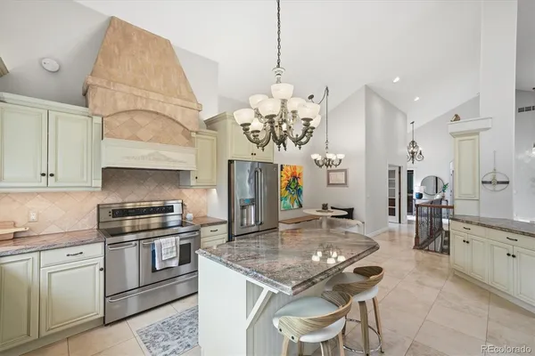 a kitchen with stainless steel appliances granite countertop a stove a sink a refrigerator and a dining table