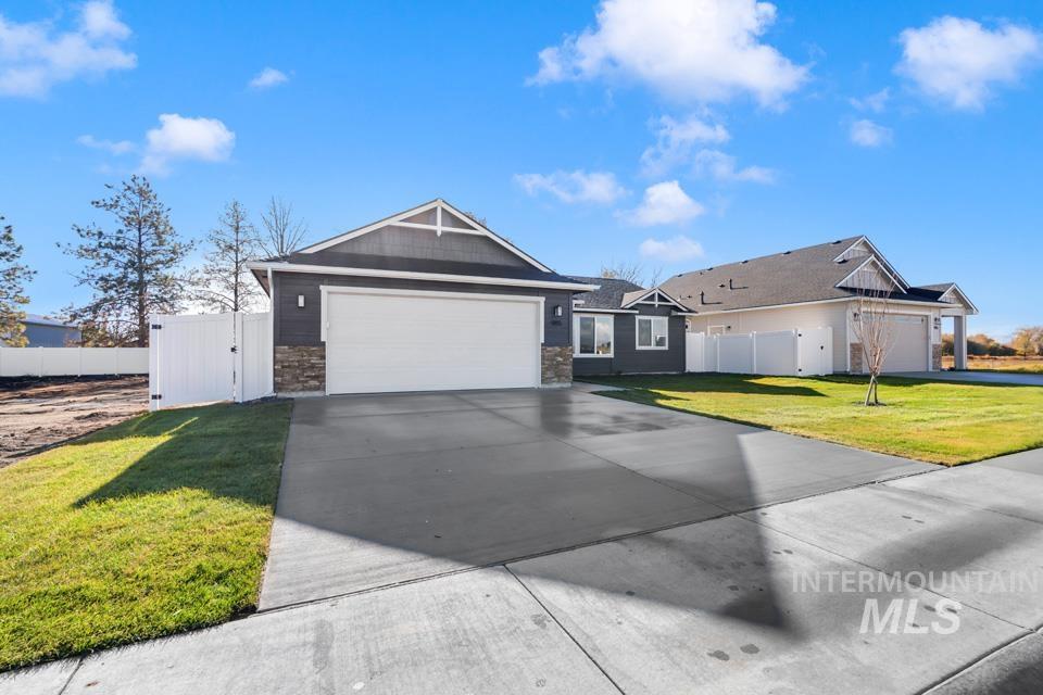 Ranch-style home featuring concrete driveway, a garage, and a gate