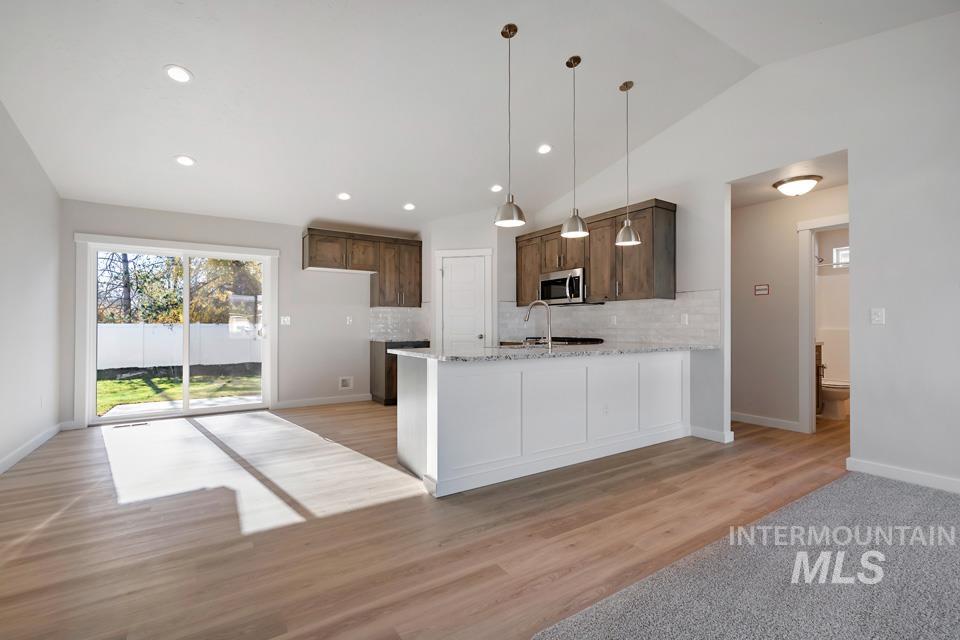 985 Twilight Street Weiser, ID 83672 - Photo 8 of 32 Kitchen with decorative light fixtures, light stone countertops, a peninsula, light wood-style floors, and dark brown cabinets