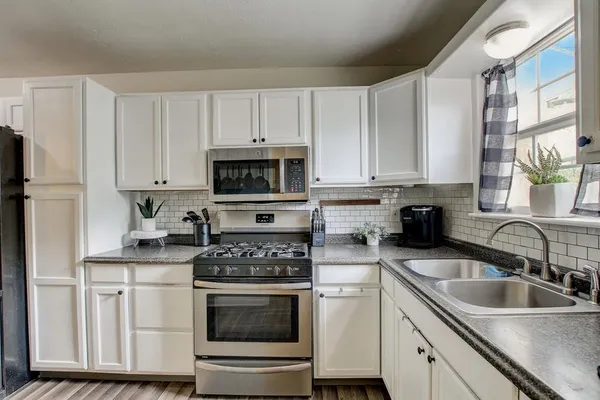 a kitchen with granite countertop white cabinets and stainless steel appliances