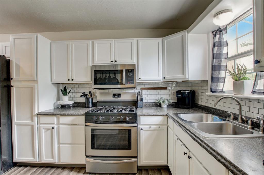 a kitchen with granite countertop white cabinets and stainless steel appliances