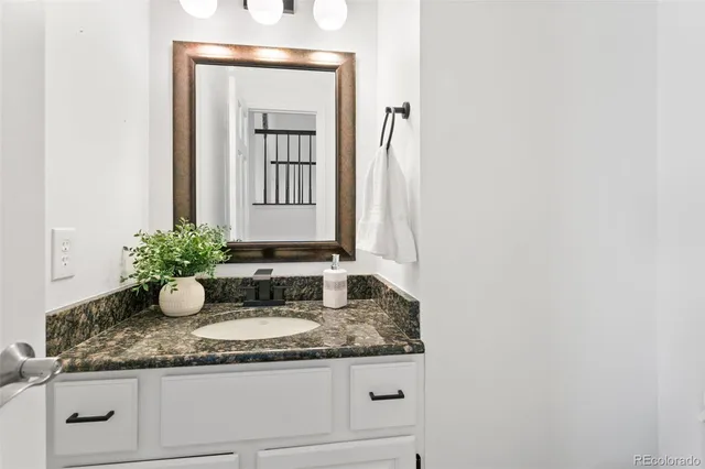 a bathroom with a granite countertop sink and a mirror
