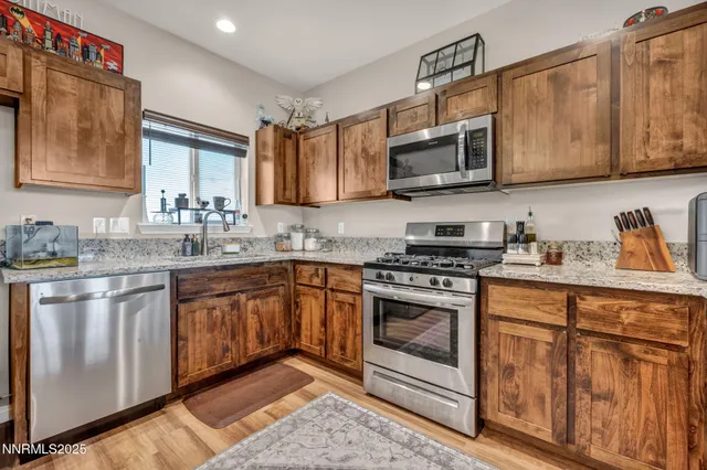 a kitchen with stainless steel appliances granite countertop a stove top oven a sink dishwasher and a microwave oven with cabinets