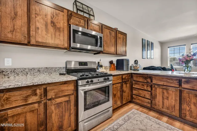 a open kitchen with stainless steel appliances granite countertop a stove a refrigerator a kitchen island a table and chairs