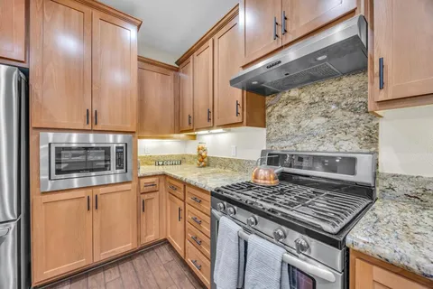 a kitchen with kitchen island granite countertop wooden floors and white stainless steel appliances