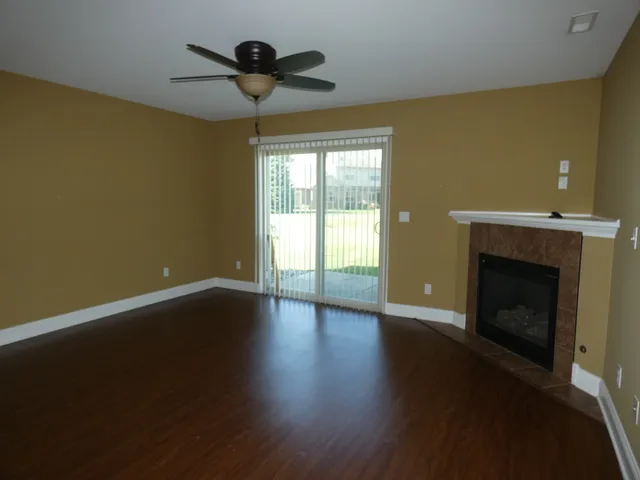 a view of an empty room with wooden floor and a fireplace