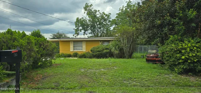 a yellow and red house sitting in the middle of a garden