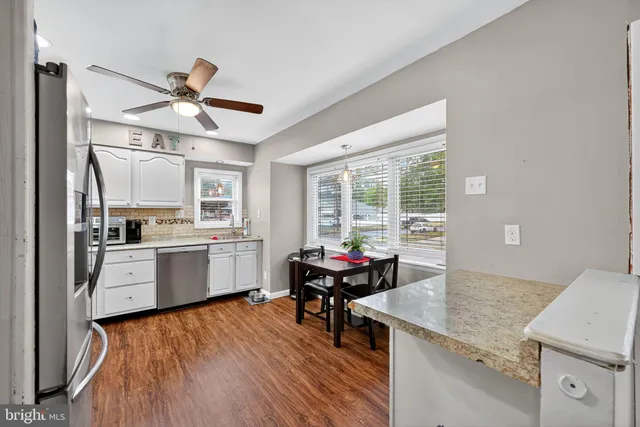 a open kitchen with stainless steel appliances granite countertop a stove and white cabinets with wooden floors