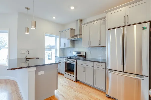 a kitchen with stainless steel appliances granite countertop a refrigerator sink and white cabinets