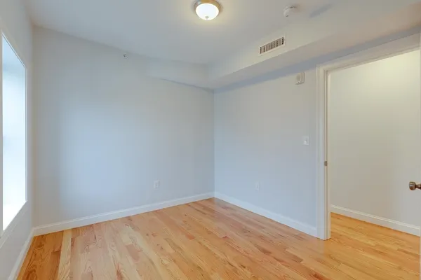 a view of an empty room with wooden floor and windows