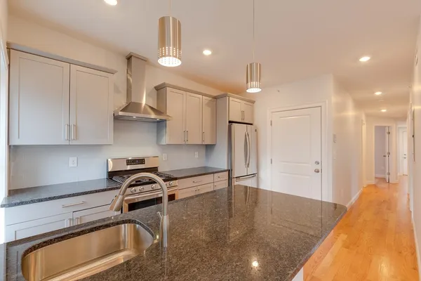 a kitchen with stainless steel appliances granite countertop a sink a stove and a refrigerator