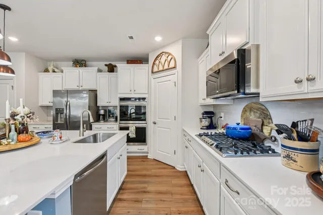 a kitchen with stainless steel appliances wooden floor and a large window