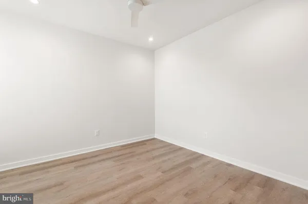 an empty room with wooden floor closet and windows