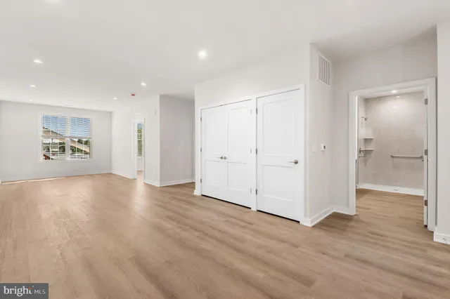 a view of an empty room with wooden floor and a bathroom