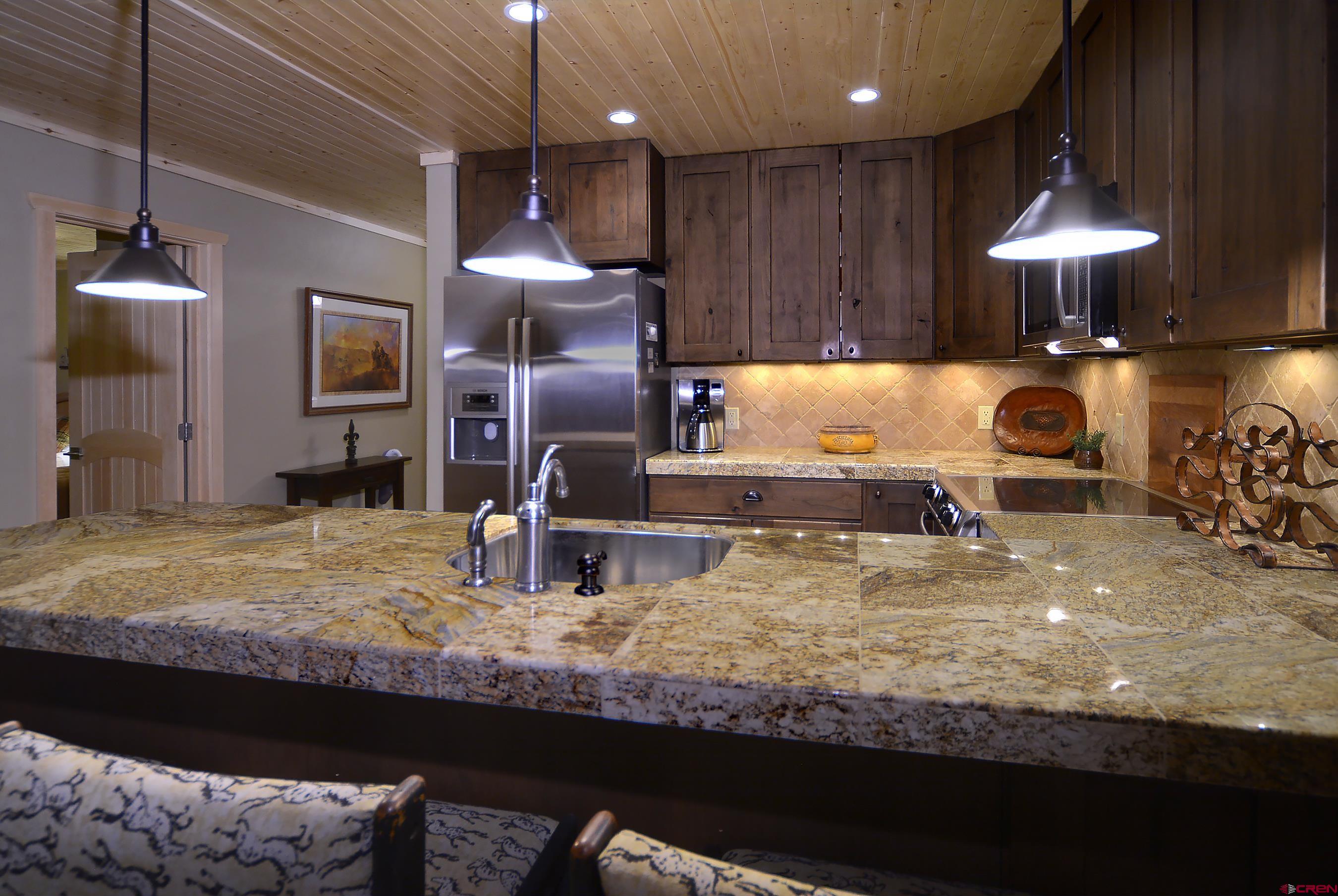 35 Emmons Road, Unit 3 Crested Butte, CO 81225 - Photo 12 of 25 a kitchen with kitchen island granite countertop a stove refrigerator and cabinets